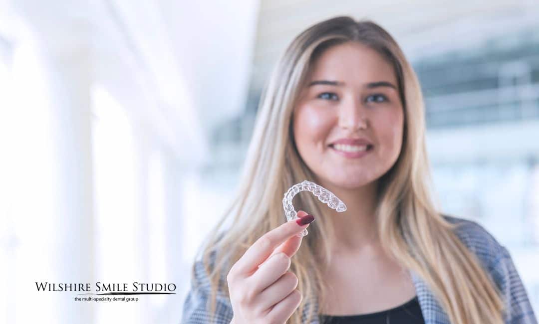 woman holding invisalign retainer in hand woman holding invisalign retainer in hand
